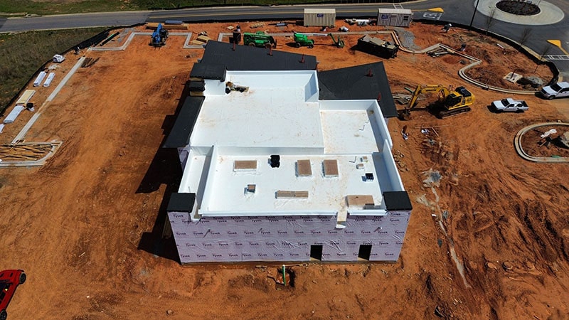 Aerial view of a large building under construction on a dirt lot.