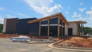 A modern building under construction features a sloped roof in one of the top roofing colors, accented by large glass windows.