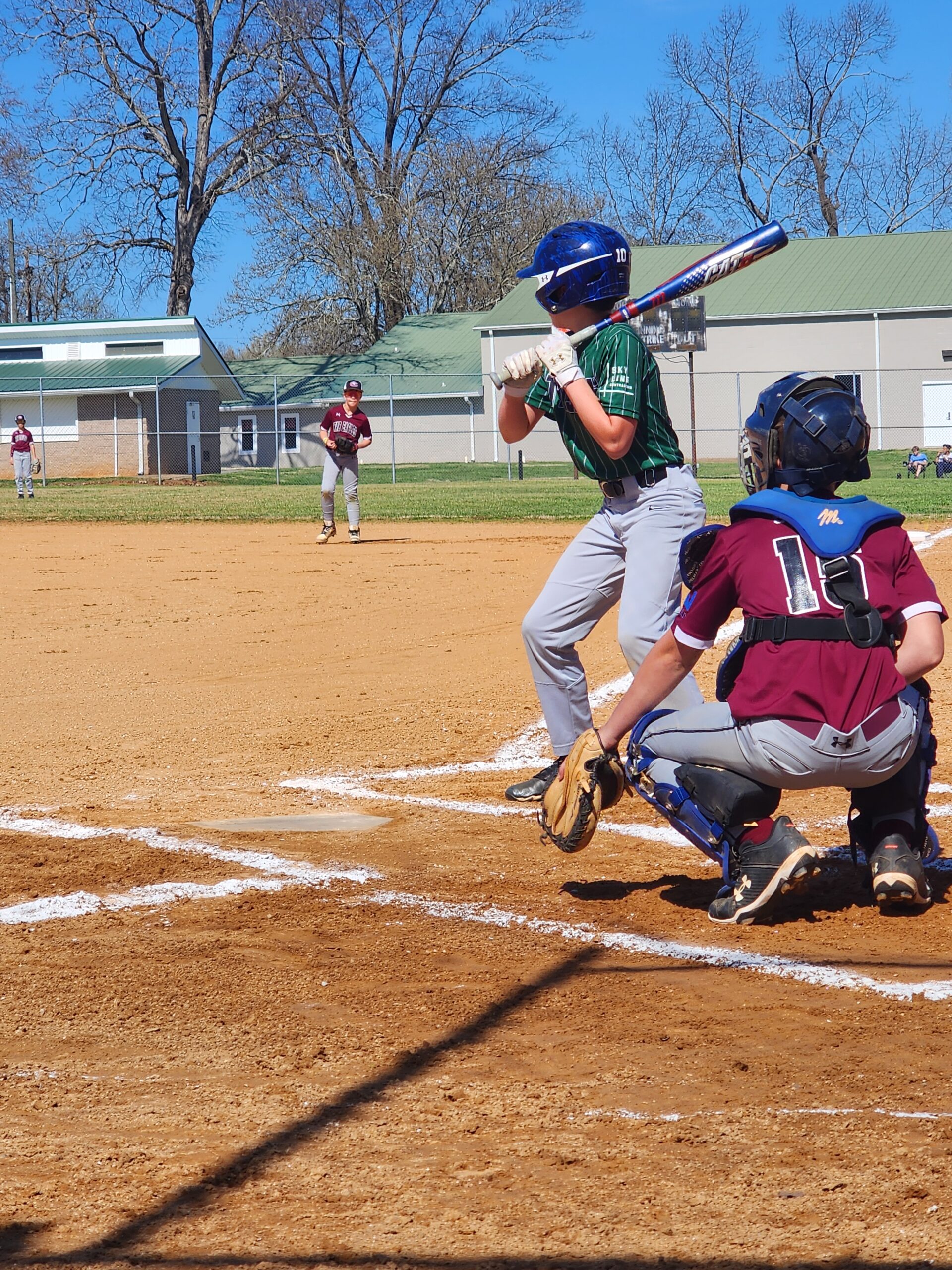 Youth baseball player batting with catcher behind them sponsored by Skyline Contracting in Gainesville, GA