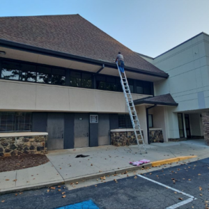 A commercial establishment with a brown roof and beige wall that is undergoing a commercial roofing services in Gainesville GA