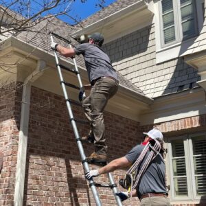 Two Skyline Contracting staff holding a ladder and stepping in the ladder in a process of roof inspection for roof replacement in Gainesville, GA